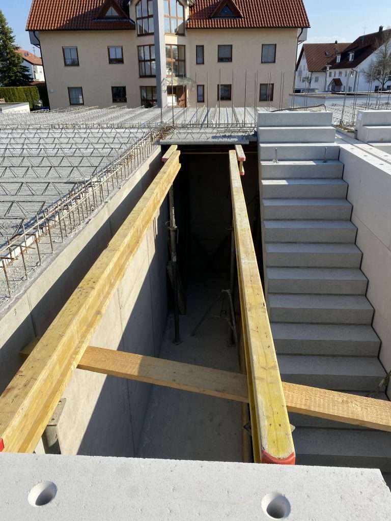 Neu betonierte Treppe ins Untergeschoss, daneben die verlegte Bewehrung der Geschossdecke mit Holzschalung und Deckenstützen