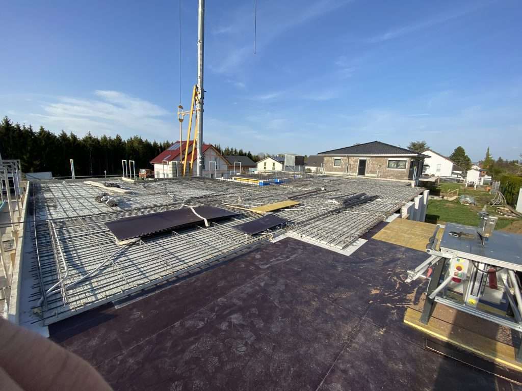 Verlegte Deckenbewehrung aus Baustahlmatten mit Leerrohren und Dämmelementen kurz vor dem Betonieren, darüber Kranseil und Betonierbühne
